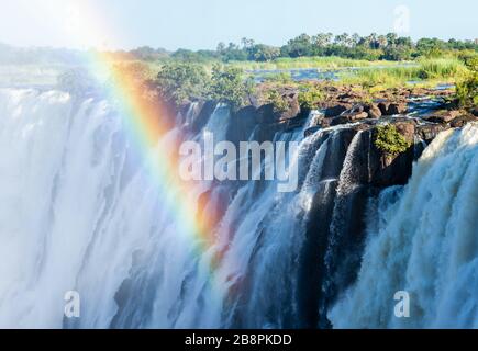 Rainbow en face de l'eau qui coule de la rivière Zambèze aux chutes Victoria, site classé au patrimoine mondial de l'UNESCO à la frontière entre la Zambie et le Zimbabwe. Banque D'Images