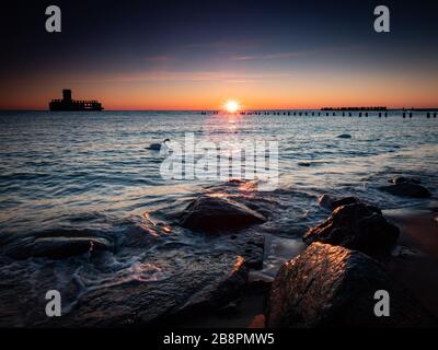 La gare de Torpedo en Allemagne, ruines de la seconde Guerre mondiale au lever du soleil. Deux cygnes blancs nagent près de la rive. Gdynia, mer Baltique, Pologne Banque D'Images