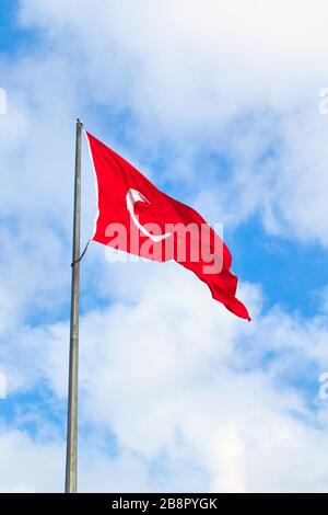 Drapeau turc agitant contre le ciel bleu nuageux. Banque D'Images