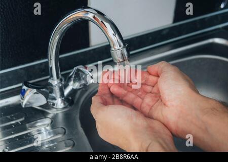 Fermez les mains mâles lavées dans un évier métallique. Un ensemble d'eau dans la paume de votre main pour laver votre visage. Procédure hygiénique le matin. Prévention Banque D'Images