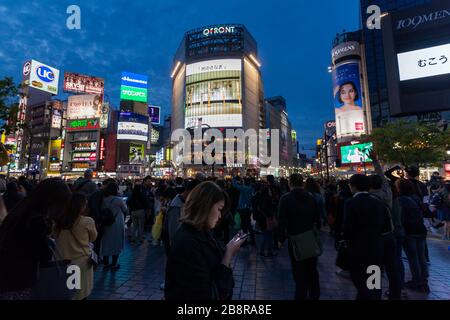 Une jeune femme utilise un smartphone devant l'emblématique Shibuya Crossing, Shibuya, Tokyo, Japon. Banque D'Images