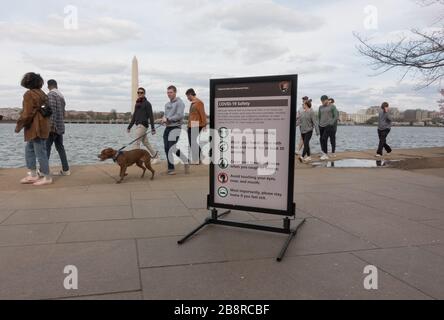 Washington, DC - Mar 22, 2020: COVID-19 panneaux d'information exhortent les précautions de sécurité dans le bassin de Tidal où les résidents et les touristes se rassemblent normalement pour voir les célèbres cerisiers en fleurs. Les responsables de la ville ont fermé les rues environnantes pour la circulation des véhicules, et deux stations de métro pour minimiser le nombre de visiteurs et la contagion possible. Banque D'Images