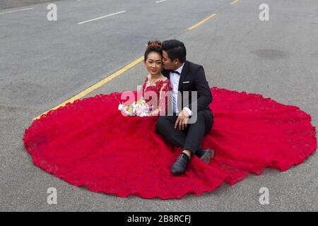 Magnifique couple Jeune heureux, un homme et une femme vêtus de tenue de mariage formelle assis dans la rue devant le Palais Royal au centre-ville de Phnom Penh Banque D'Images