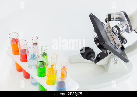 Tubes à essai dans un support et un microscope sur une table blanche Banque D'Images