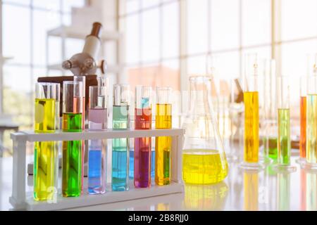 Flacons de réactifs chimiques, flacons d'expériences scientifiques de différentes formes, tailles et microscopes sur la table Banque D'Images