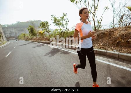 femme de sport courir sur sideroad. femme de sport courir sur la route vide Banque D'Images