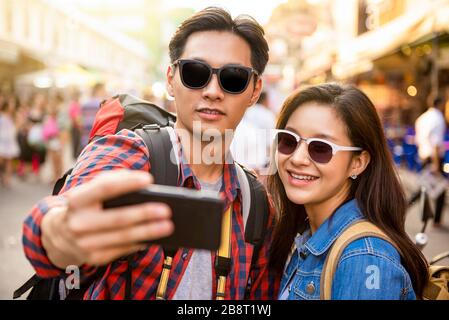 Jeunes touristes asiatiques souriants prenant selfie en voyageant à Khao San Road Bangkok Thaïlande pendant les vacances d'été Banque D'Images