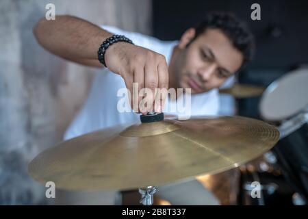 Jeune homme aux cheveux sombres dans un t-shirt blanc qui a l'air occupé Banque D'Images
