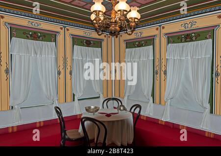 Coin confortable dans une ancienne maison traditionnelle bulgare avec une table et des chaises anciennes du XIXe siècle à la fenêtre avec des rideaux, Panagyurishte, B Banque D'Images