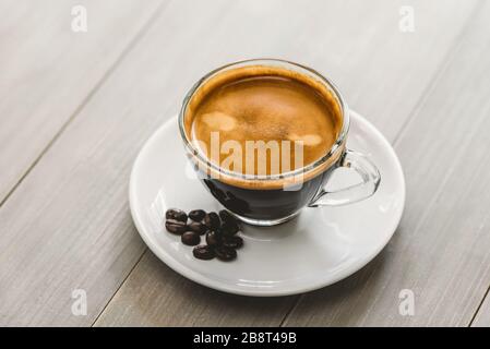 Une tasse fraîche de café expresso préparé servi sur une soucoupe à la table en bois vintage Banque D'Images