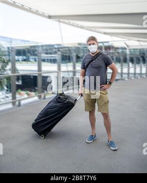 Interdiction et restrictions de voyage liées à l'éclosion de coronavirus. Voyageur homme avec masque de face à l'aéroport international affecté par l'annulation de vol. COVID-19 pande Banque D'Images