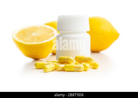 Capsules de vitamines. Pilules de vitamine C avec flacon de pilule et fruits de citron isolés sur fond blanc. Banque D'Images
