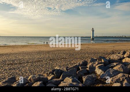 Couple chien de marche sur la plage près du coucher du soleil avec Perch rock phare New Brighton Merseyside Angleterre Banque D'Images
