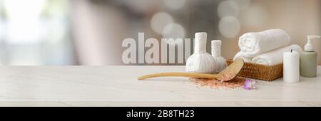 Photo courte d'accessoires de spa avec serviette blanche, bougie, huile d'arôme, balles de compression à base de plantes et espace de copie sur table en marbre Banque D'Images