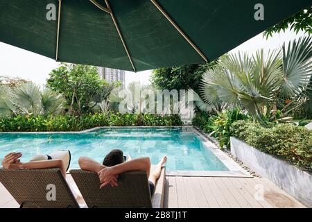 Les jeunes couples qui apprécient de passer du temps en profitant de la piscine isolée du petit hôtel de spa de la grande ville Banque D'Images