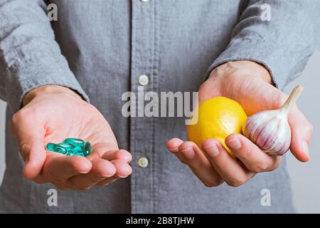 Les mains de l'homme se rapprochent des pilules dans une main et du citron avec l'ail dans l'autre. T Banque D'Images