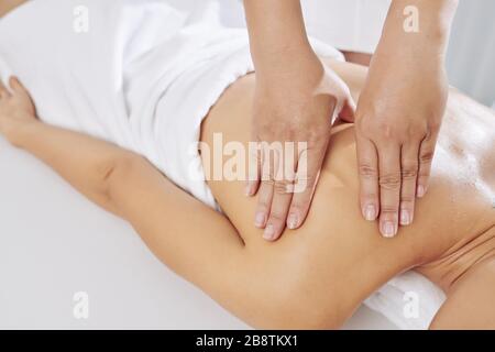 Image rapprochée du massothérapeute appliquant une pression soutenue en utilisant des traits lents et profonds pour cibler les couches intérieures des muscles Banque D'Images