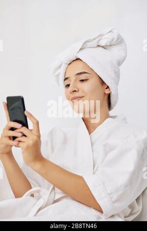 Belle jeune femme en peignoir de bain et serviette sur sa tête prenant selfie après la douche Banque D'Images