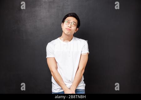 Charmant et charmant homme gay asiatique soupirant et regardant vers le haut, rêvant ou l'imagerie quelque chose de romantique, tenir les mains ensemble posture modeste Banque D'Images