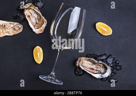 Huîtres fraîches ouvertes, glace, citron et un verre de vin blanc Banque D'Images