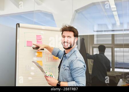 Jeune homme en tant qu'entrepreneur de démarrage réussi sur le tableau de conférence de l'agence Internet Banque D'Images
