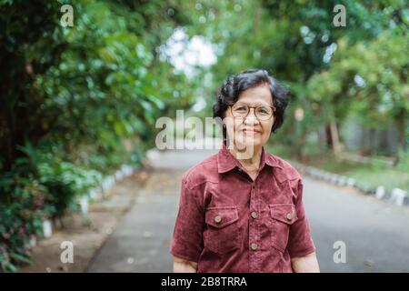 grand-mère souriant avec lunettes de vue marchant dans le parc Banque D'Images