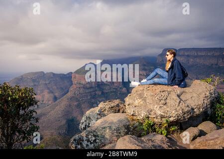 Femme caucasienne assise sur le rocher au canyon de la rivière Blyde Mpumalanga Afrique du Sud Panorama route panoramique en admirant la vue panoramique Banque D'Images