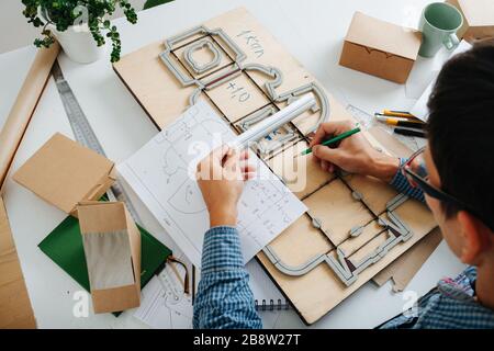 Vue de dessus du concepteur d'emballages du lieu de travail. L'homme travaille sur la table Banque D'Images
