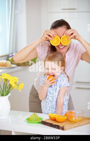 Famille avec mère et enfant presser le jus frais d'oranges dans la cuisine Banque D'Images