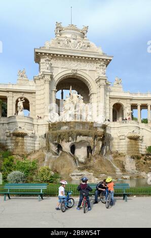 Jeunes garçons vélos d'équitation ou vélos et port de casques devant le Palais Longchamp ou le Palais Longchamp et la fontaine Marseille Provence France Banque D'Images