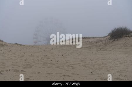 Ferris à carrousel solitaire dans les dunes de sable sur brouillard épais vu à Sunny Beach, Bulgarie au printemps hors saison Banque D'Images