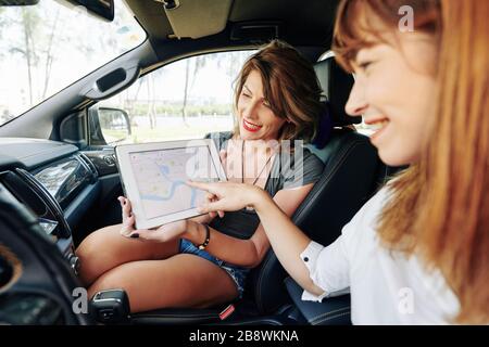 Jeune femme pointant à un endroit aléatoire sur la carte où les amis vont monter le week-end Banque D'Images