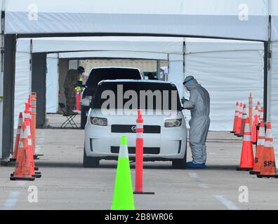 Miami Gardens, Floride, États-Unis. 22 mars 2020. Le travailleur de la santé se prépare à écouvier un chauffeur au Hard Rock Stadium de Miami Gardens, en Floride. DeSantis a parlé au stade où la Garde nationale a ouvert un site d'essais au drive du coronavirus. Le dimanche, ils n'ont testé que les premiers intervenants. Lundi, ils ont prévu de l'étendre à des personnes d'au moins 65 ans qui présentent des symptômes de la maladie le 22 mars 2020 dans les jardins de Miami, en Floride. Crédit : Mpi10/Media Punch/Alay Live News Banque D'Images
