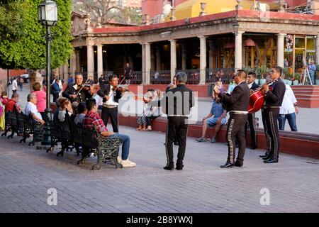 Groupe mexicain Mariachi jouant pour la foule assis sur un banc de parc sur la place centrale de San Miguel de Allende Banque D'Images