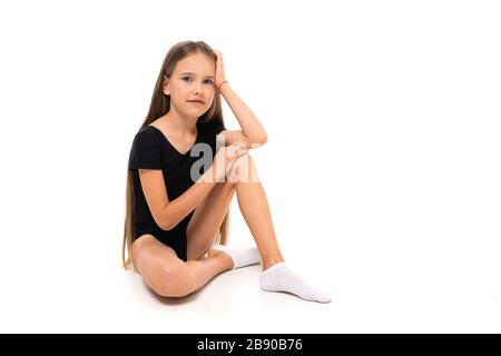 une jeune fille gymnast assise sur le sol sur un fond blanc avec espace de copie Banque D'Images