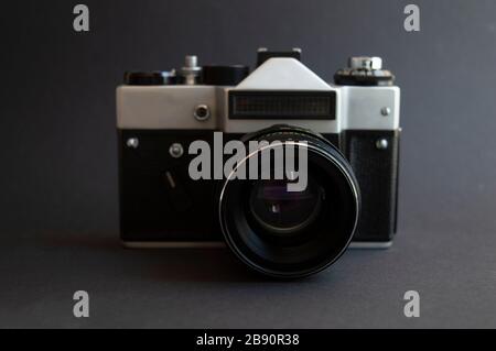 Appareil photo à film vintage sur fond sombre. Cadre noir en métal argenté et en plastique avec objectif. Banque D'Images
