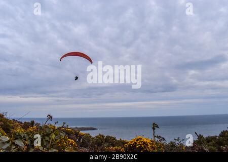 Concept de succès. Un homme parapente dans un ciel clair sur la côte de l'Irlande Banque D'Images