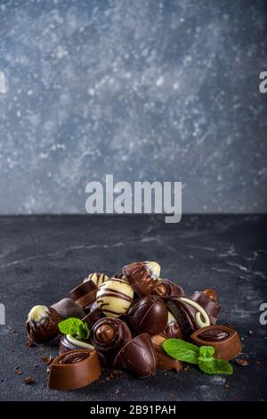 Diverses bonbons au chocolat sur fond sombre. Différents bonbons et chocolats avec feuilles de menthe, espace de copie Banque D'Images