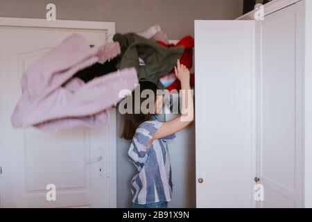 Une adolescente jette des vêtements hors de son placard Banque D'Images