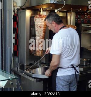 Athènes, Grèce - 14 septembre 2019: Tranche d'homme de morceaux de viande pour souvlaki de la machine de rôtisserie gyros. Banque D'Images