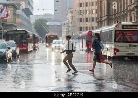 Les femmes traversent Bahnhofplatz dans un grand orage, Winterthur, Suisse. Banque D'Images