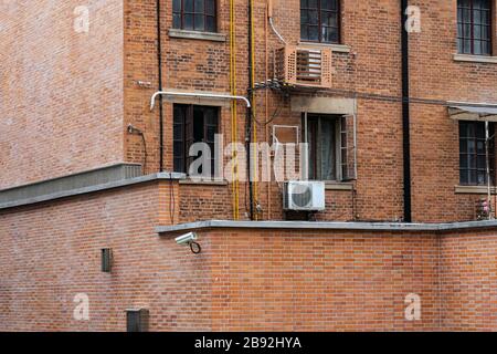 Mur extérieur de l'hébergement résidentiel traditionnel Shanghainais. Briques rouges et fenêtres avec unité de climatisation externe sur l'extérieur de OL typique Banque D'Images