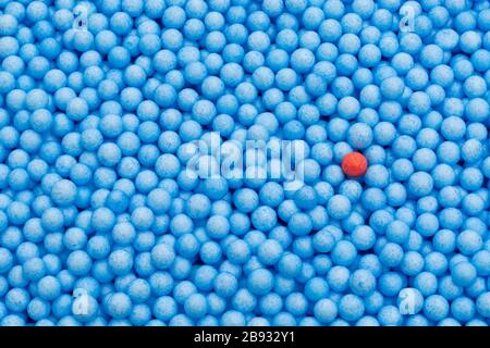 Petites boules de polystyrène bleu et rouge de couleur. Conceptuel pour l'auto-isolation de Covid-19, porteur de maladie, personne infectée, isolée, perdue dans la foule. Banque D'Images