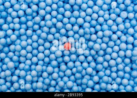 Petites boules de polystyrène bleu et rouge de couleur. Conceptuel pour l'auto-isolation de Covid-19, porteur de maladie, personne infectée, isolée, perdue dans la foule. Banque D'Images