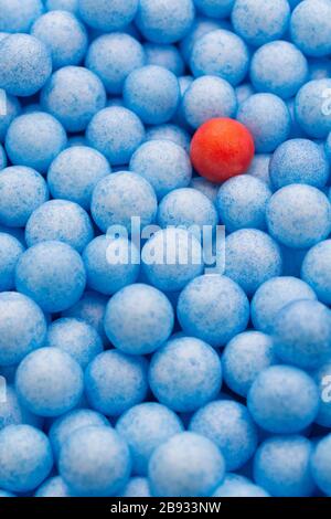 Petites boules de polystyrène bleu et rouge de couleur. Conceptuel pour l'auto-isolation de Covid-19, porteur de maladie, personne infectée, isolée, perdue dans la foule. Banque D'Images