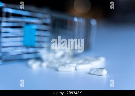 pile de pilules médicinales blanches déversées sur une table à partir d'un panier miniature Banque D'Images