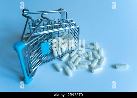 pile de pilules médicinales blanches déversées sur une table à partir d'un panier miniature Banque D'Images