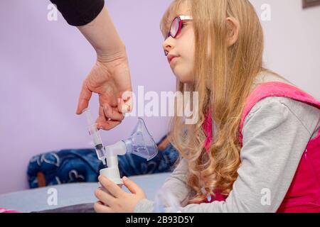 La femme prépare un traitement par inhalation pour les enfants souffrant de problèmes asthmatiques, de thérapie à domicile. Banque D'Images