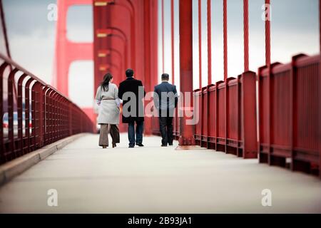 Trois amis marchent ensemble sur le Golden Gate Bridge, San Francisco, États-Unis. Banque D'Images