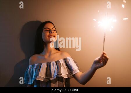 Fille avec pulvérisateur en main devant le mur gris Banque D'Images